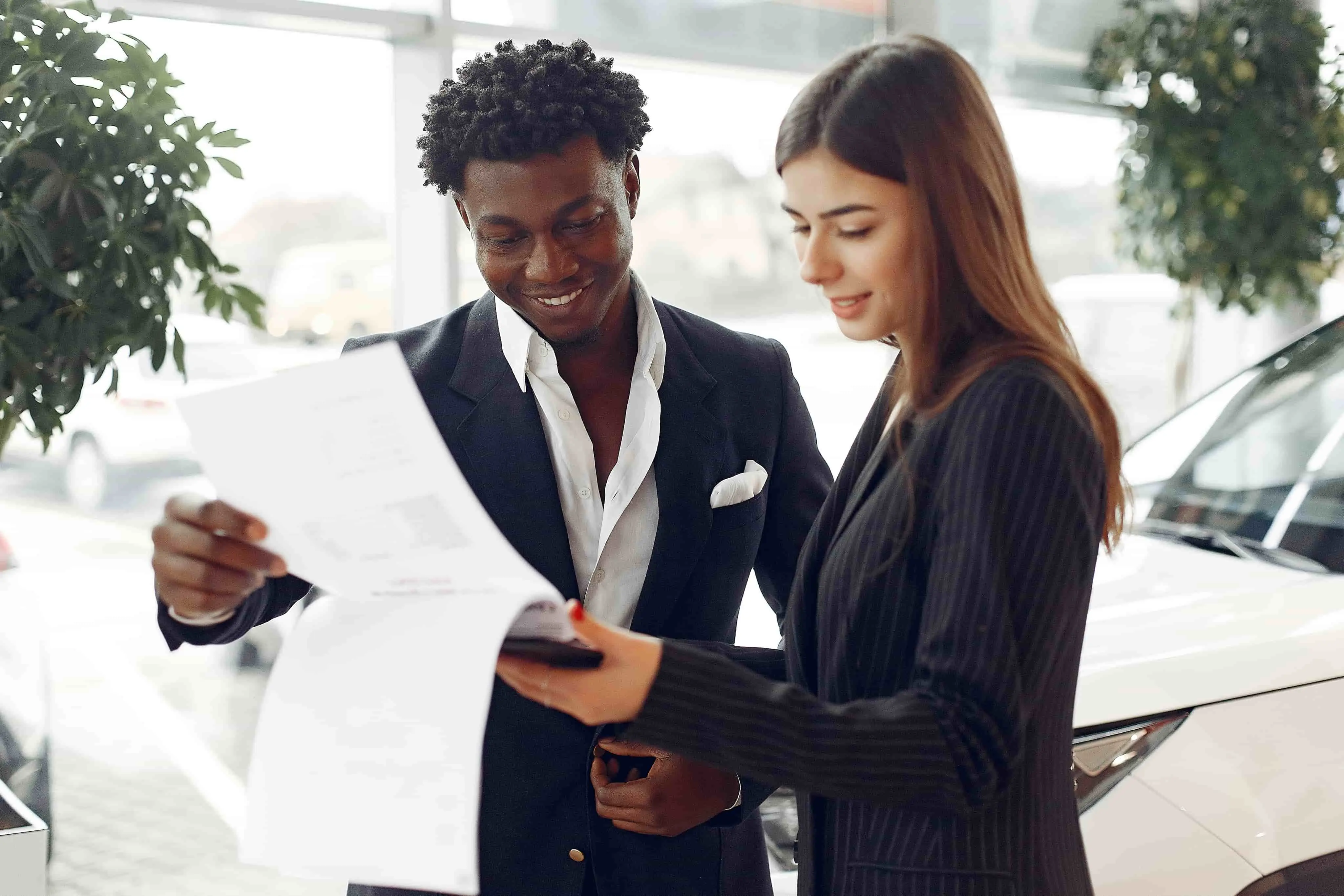 man and woman at a car dealership discussing car financing