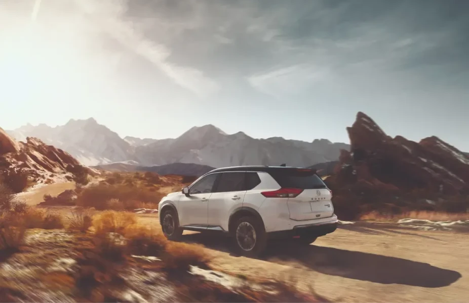 White Nissan SUV driving through a desert mountain landscape