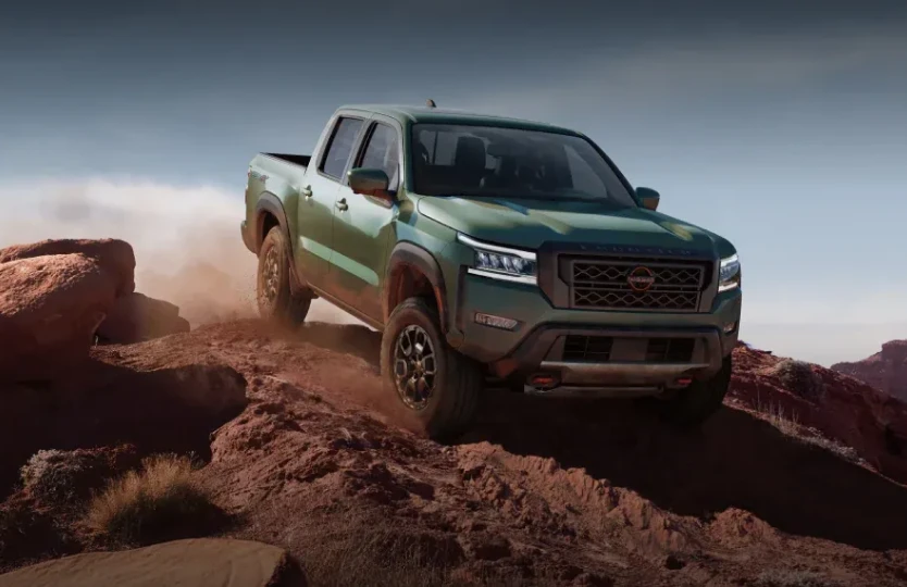 Green Nissan truck driving over rocky off-road terrain