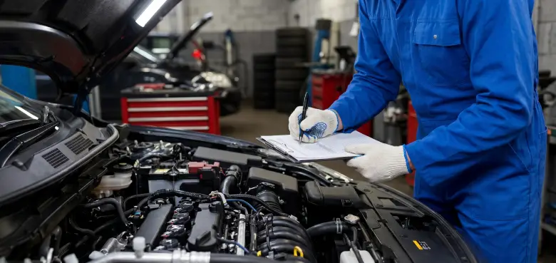 Technician reviewing a service checklist beside an open engine bay at Aros Automotive in Gainesville, GA