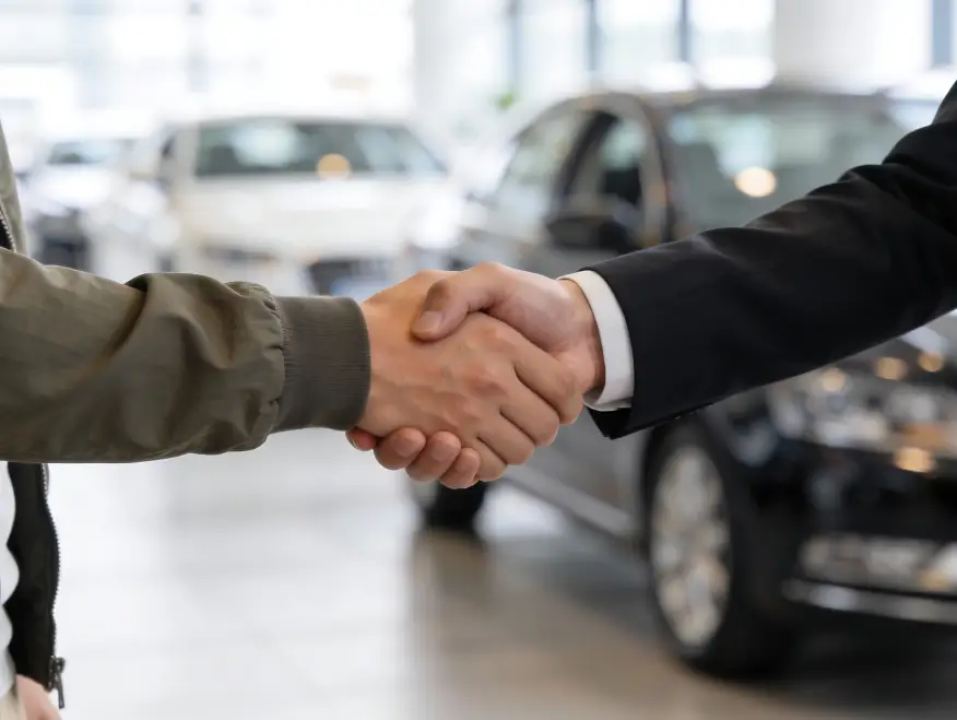 Customer shaking hands with a dealership representative in a showroom