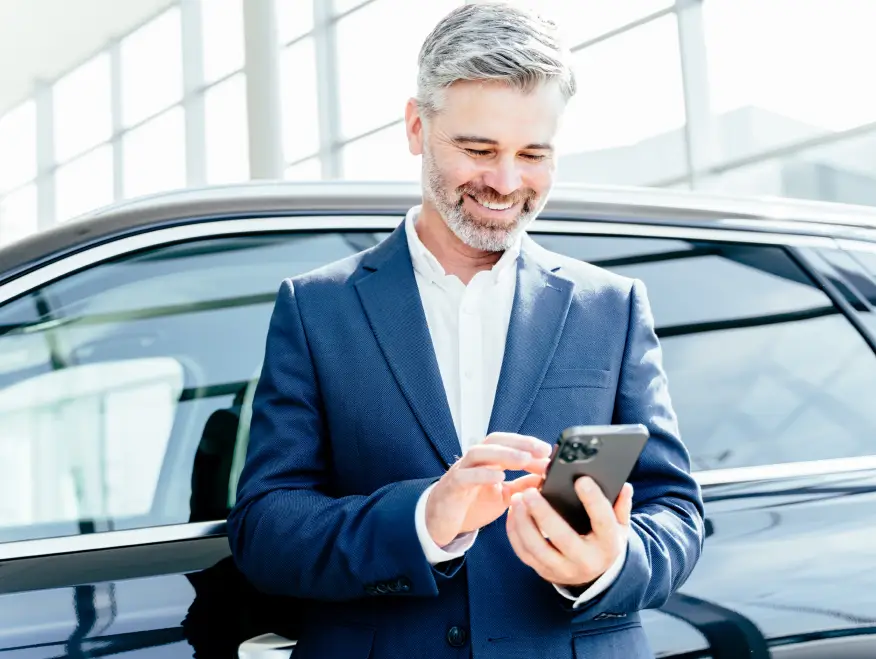 Customer using a phone to check vehicle value beside a car