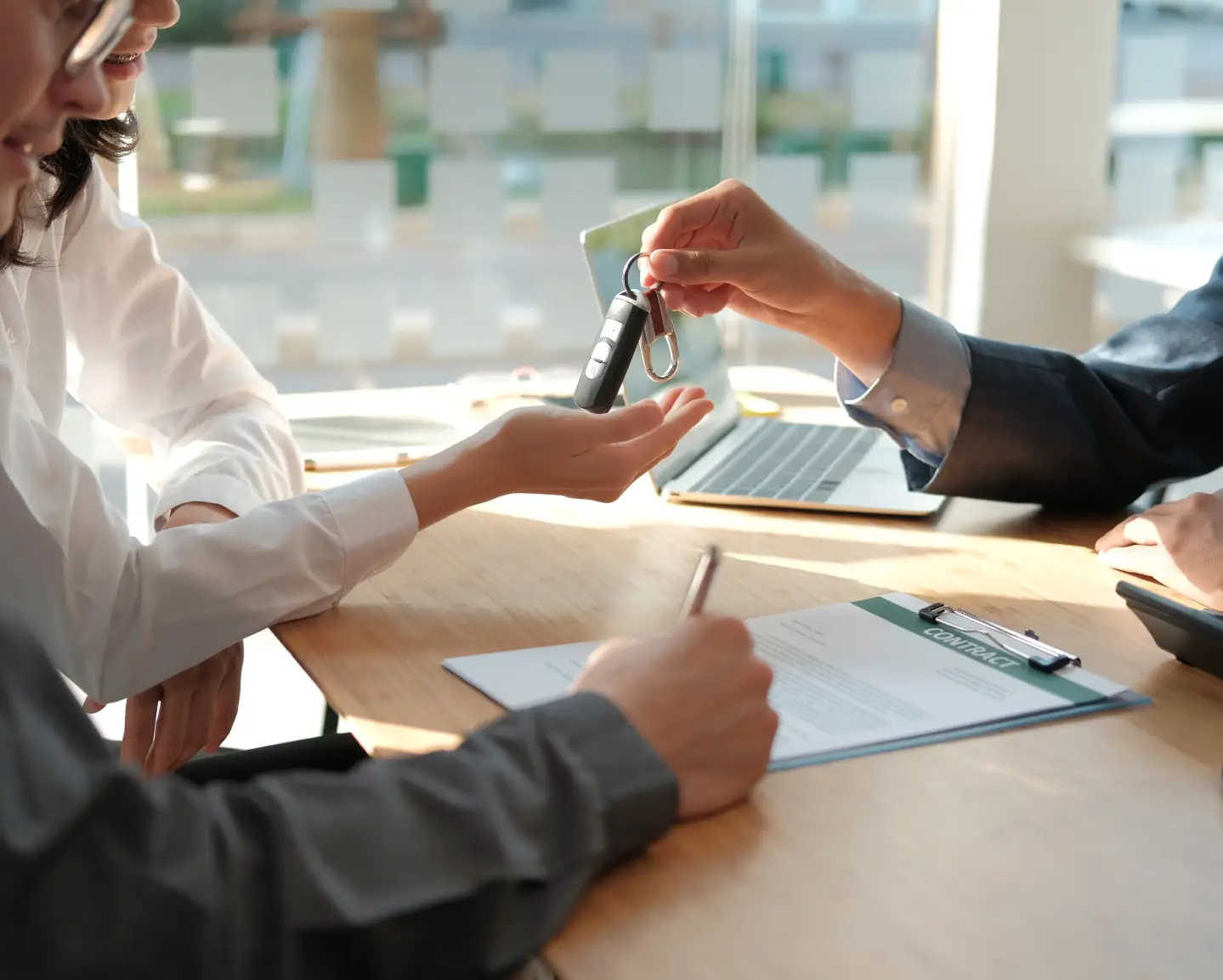 Customer receiving car keys after signing purchase agreement.