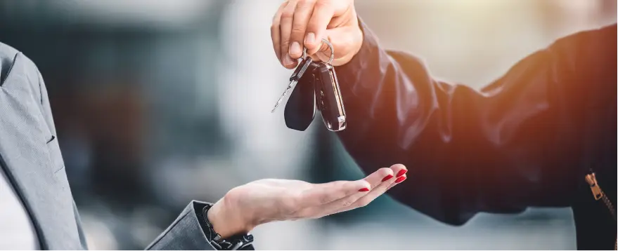 Person handing over car keys during a vehicle sale or trade