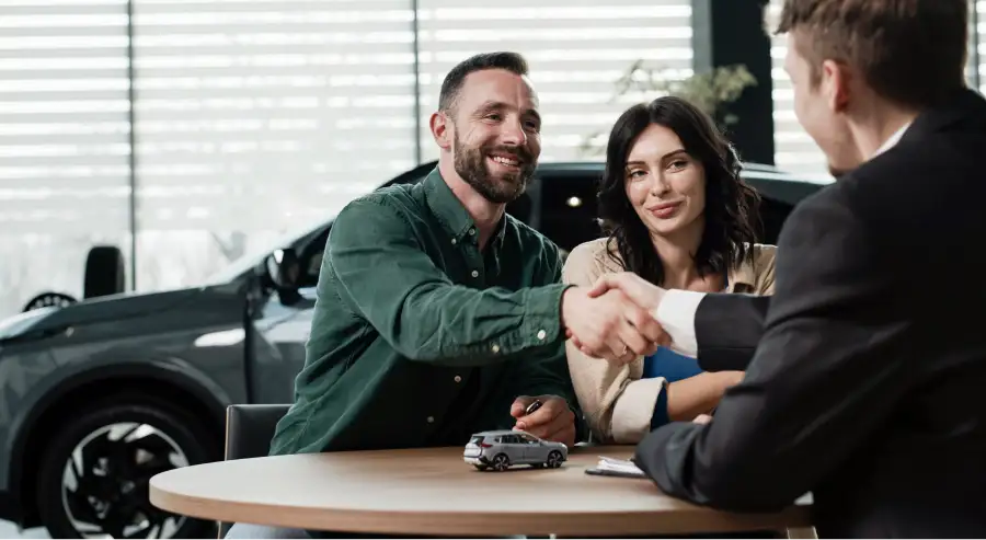 Couple shaking hands with an Auto Sense North sales advisor after getting approved for a car loan near Concord, NH