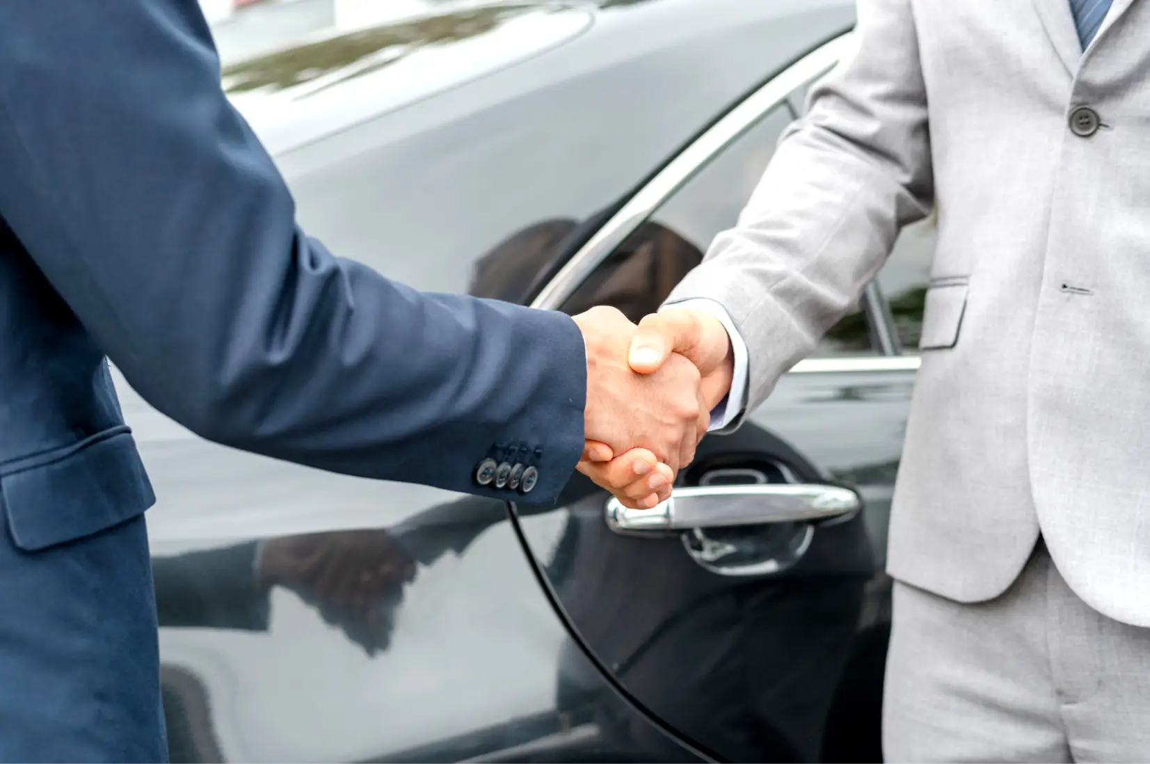 Customer shaking hands with a dealership representative near a vehicle at Cars614.
