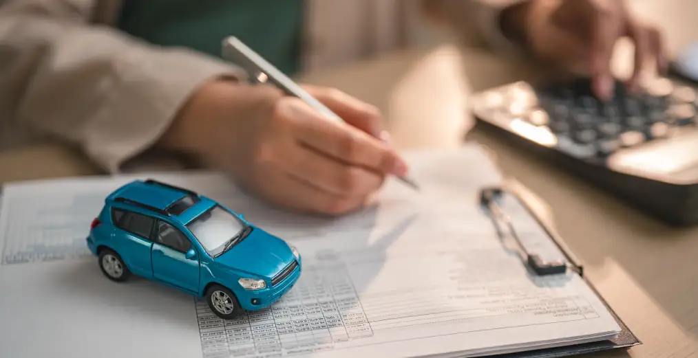 Vehicle financing paperwork with model car during the auto loan process