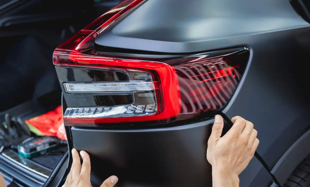 Auto body technician installing a rear light during collision repair service