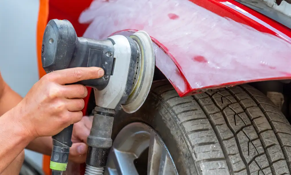 Technician polishing a vehicle fender during auto body repair service