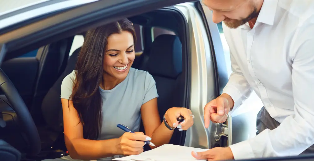 Customer signing vehicle paperwork with Autos of Chicago team member during the buying process
