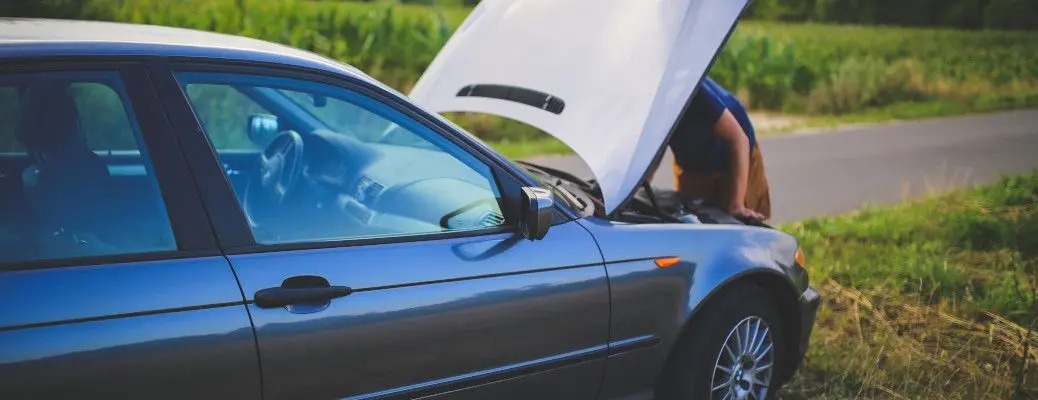 A man who may have flooded his engine checking under the hood.