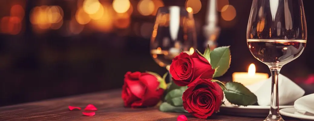 Red roses and wine glasses on a table.