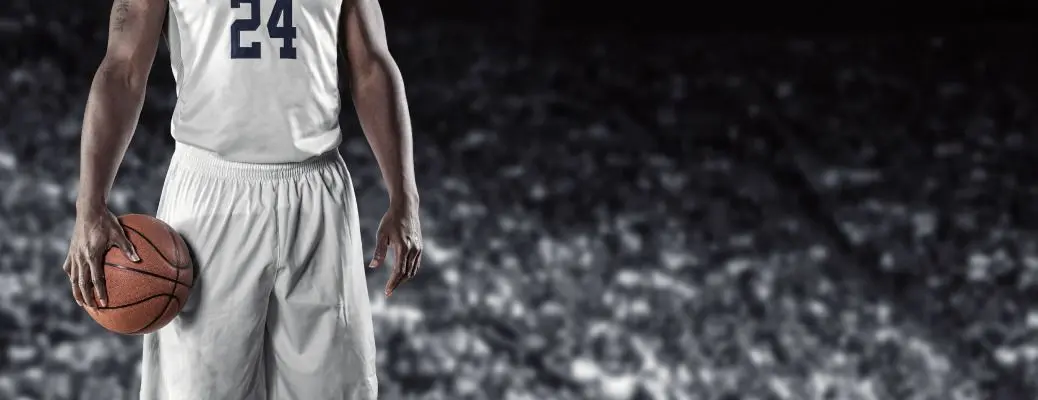 A basketball player in the foreground with fans in the background.