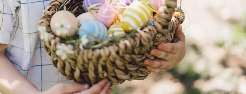 A child holding a basket filled with Easter eggs.