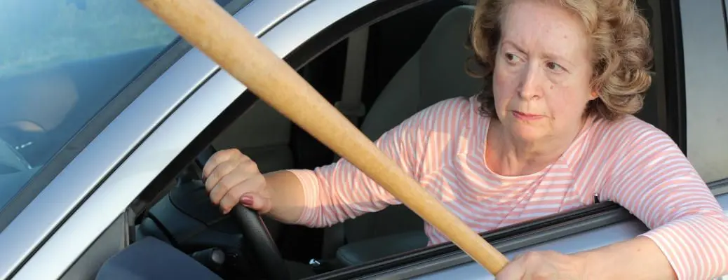 Angry mature female driver holding baseball bat