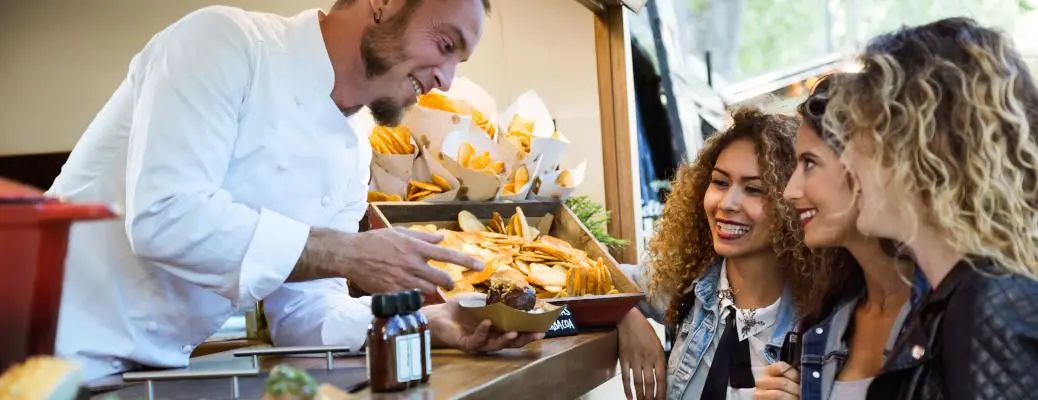 Three beautiful young women buying meatballs on a food truck.