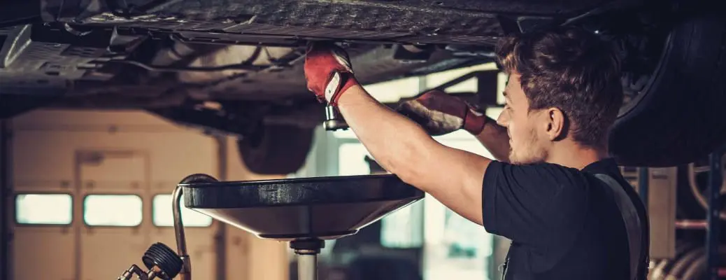 A man draining oil out of a car.