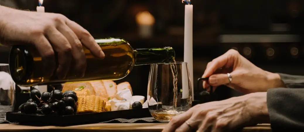Image of people pouring wine on a candlelit table.