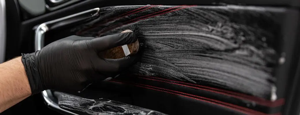 A person cleaning the leather interior of a car.