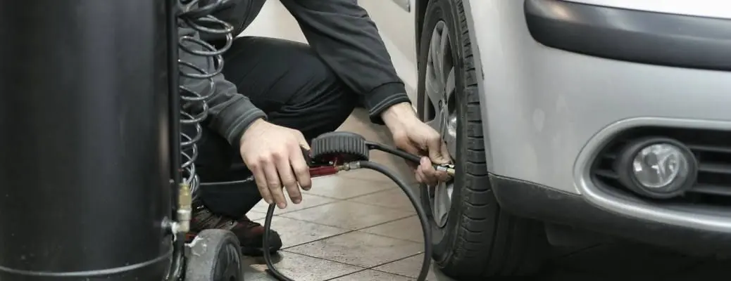 A man filling a car's tire with air.