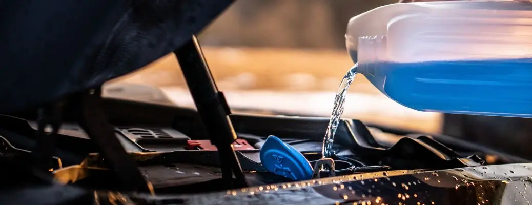 Pouring wiper fluid into the reservoir.
