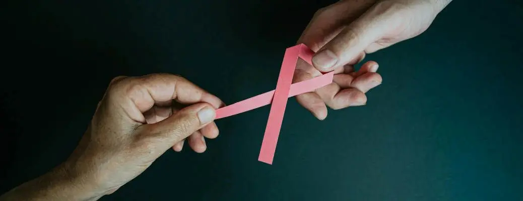 Two hands holding the breast cancer awareness ribbon.