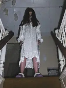 An apparition at the top of the stairs of a haunted house.