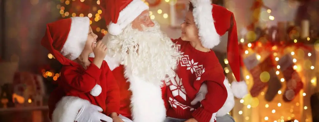Cute little boy and girl with Santa Claus in room decorated for Christmas