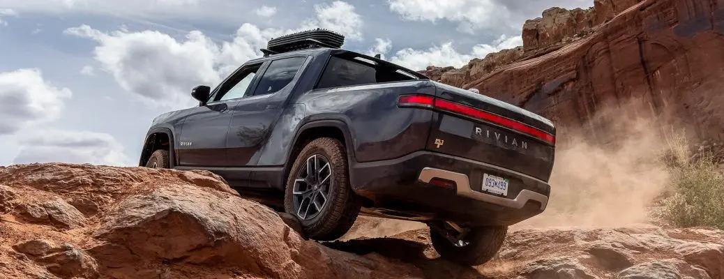 A Rivian R1T driving over rocky terrain.