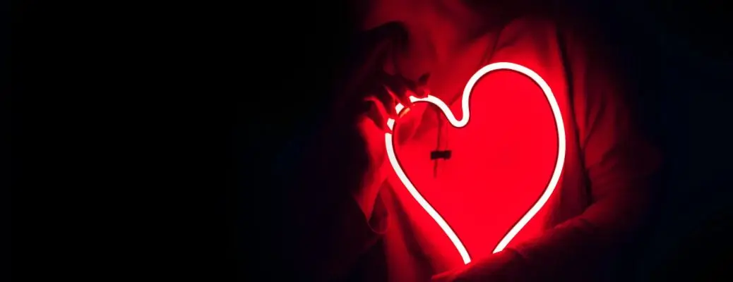An image of a woman holding a neon heart