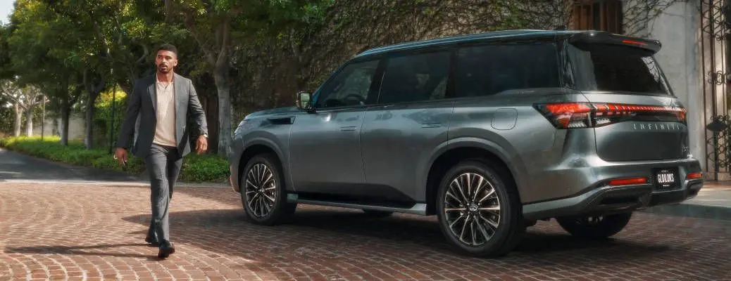 A man standing near a used Infiniti QX80 near Dallas.