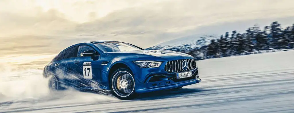 A Mercedes-Benz performance car being driven aggressively in the snow.