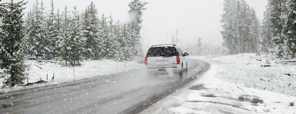 An SUV driving safely on a snowy road.