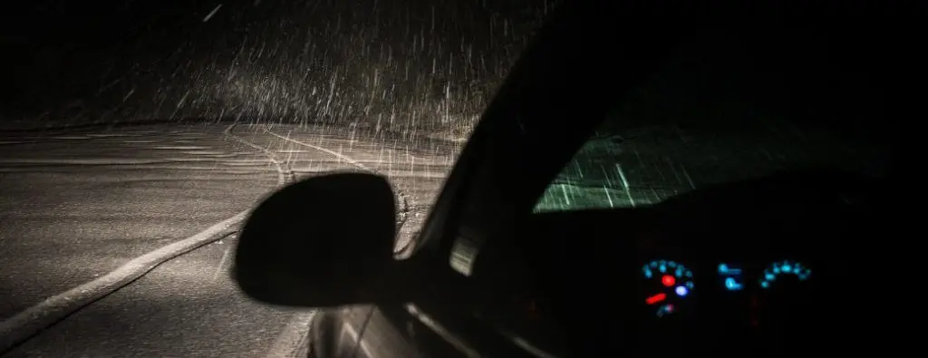 A car driving in the snow at night.