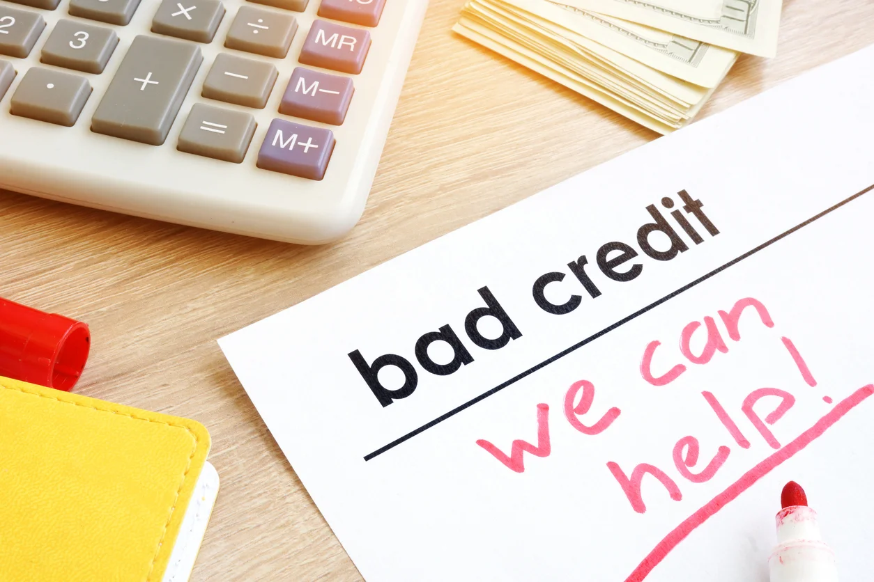 Documento con la frase "bad credit we can help!" junto a una calculadora y dinero en Baja Auto Sales.