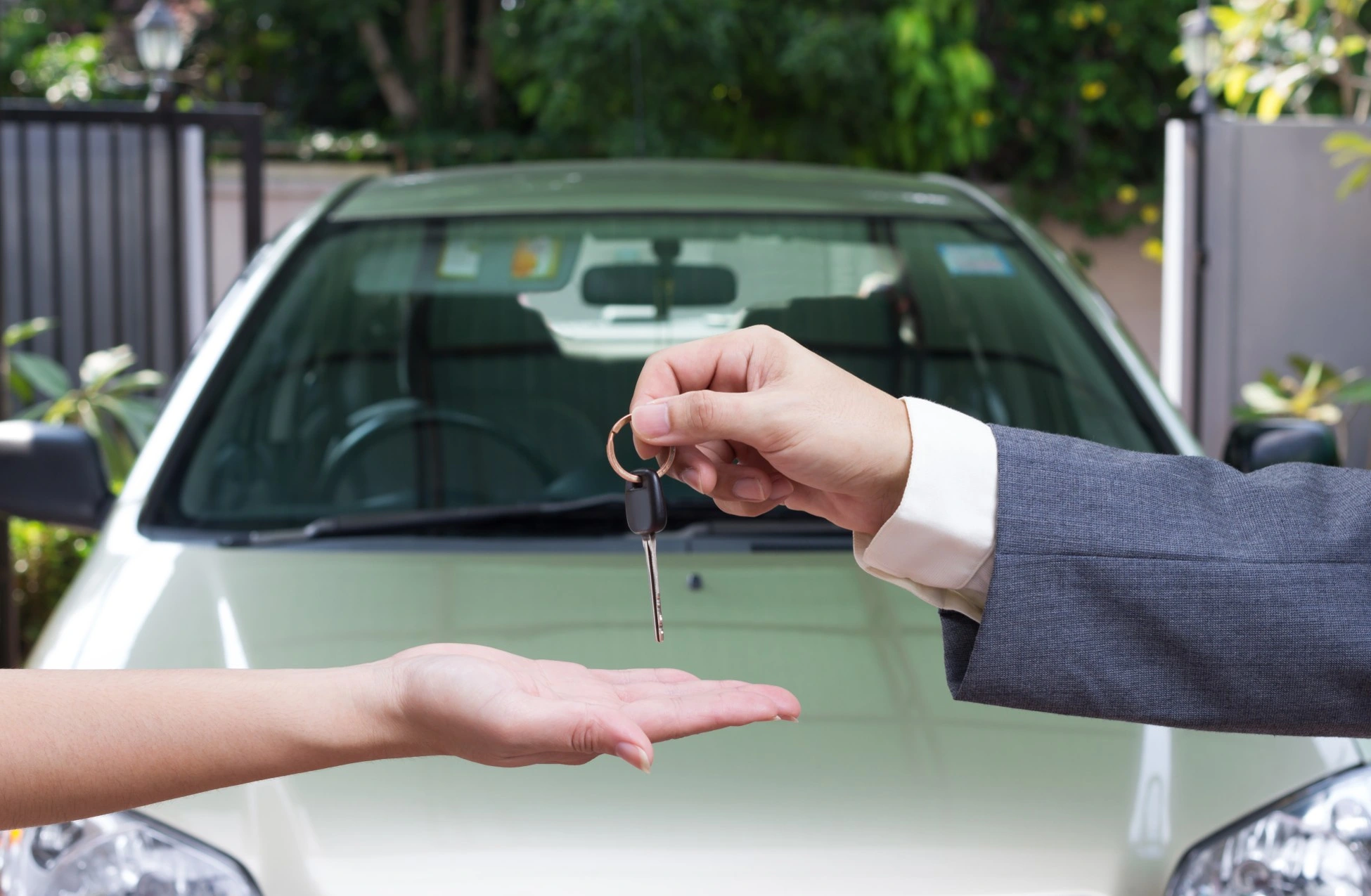 Vendedor de autos entregando llaves a un cliente frente a un vehículo.