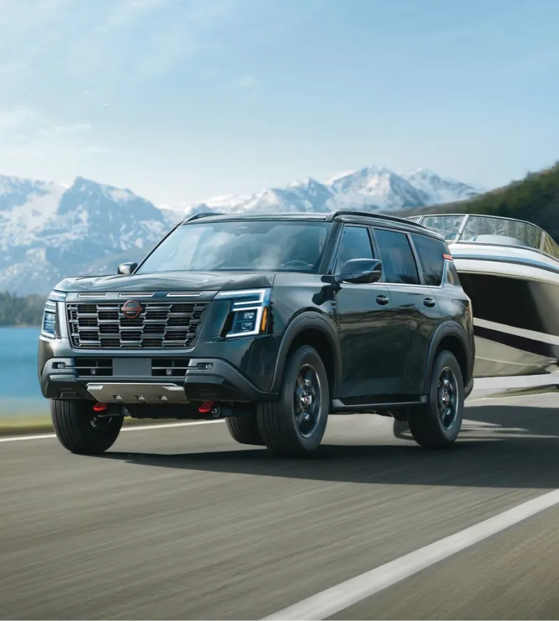 Nissan SUV towing a boat on a scenic mountain road