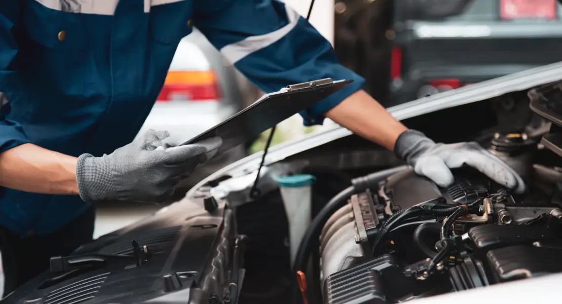 Technician inspecting a car engine during auto service