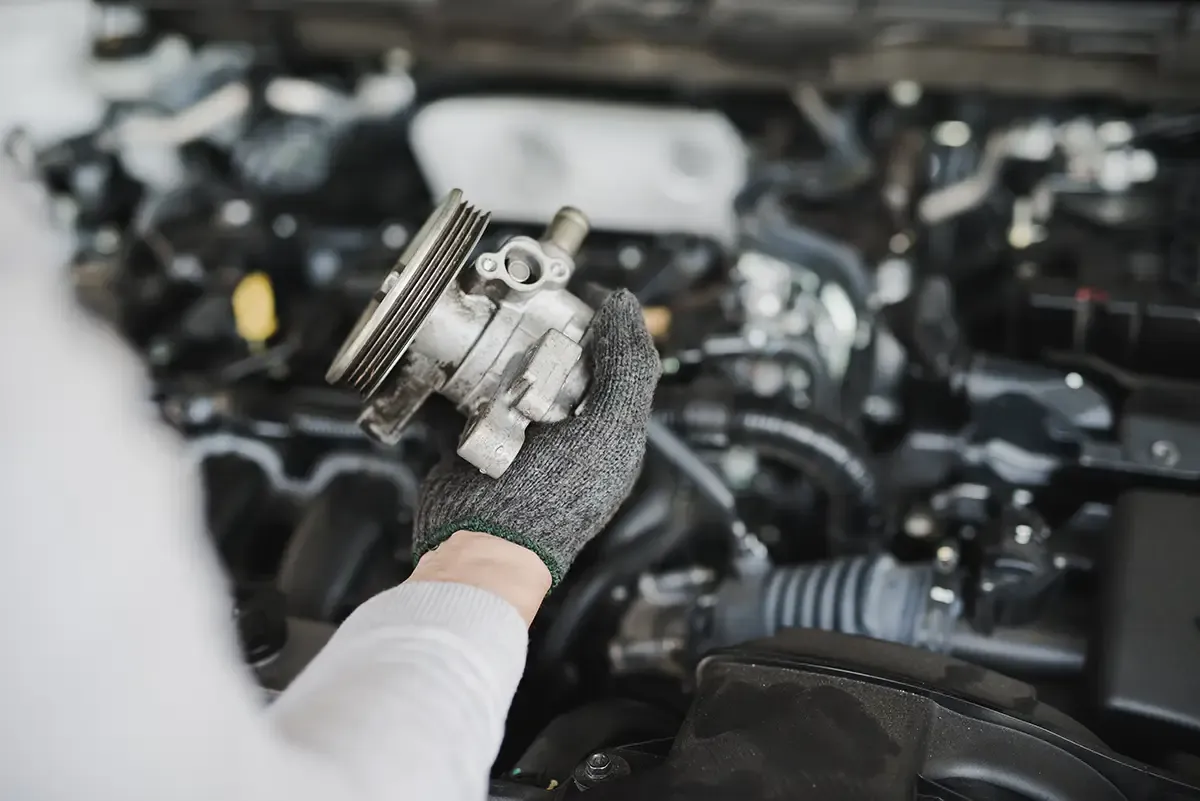 Technician inspecting an auto part during engine service at BLVD Auto Inc