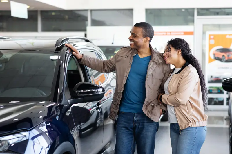 Couple looking at a used SUV inside a dealership showroom at BLVD Auto Inc