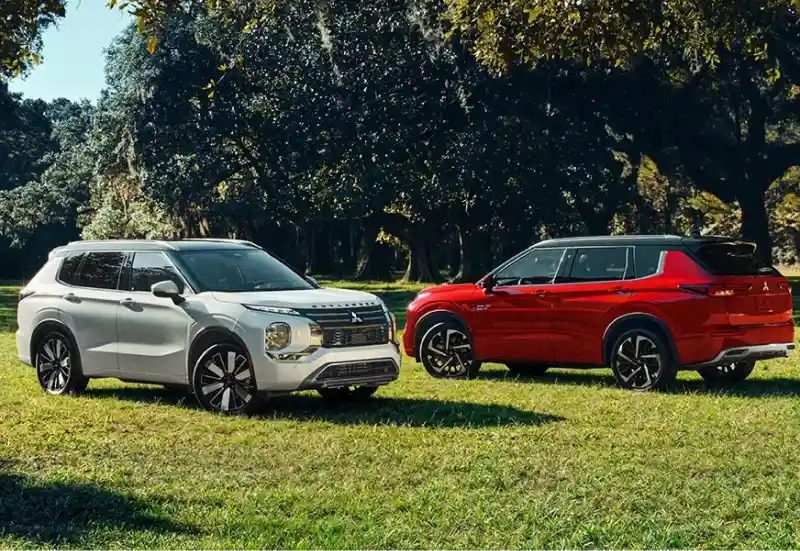 White and red Mitsubishi Outlander SUVs parked on grass during the Mitsubishi Summer Sales Event.