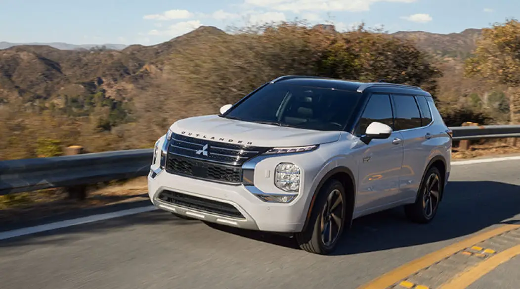 White Mitsubishi Outlander driving on a mountain road.