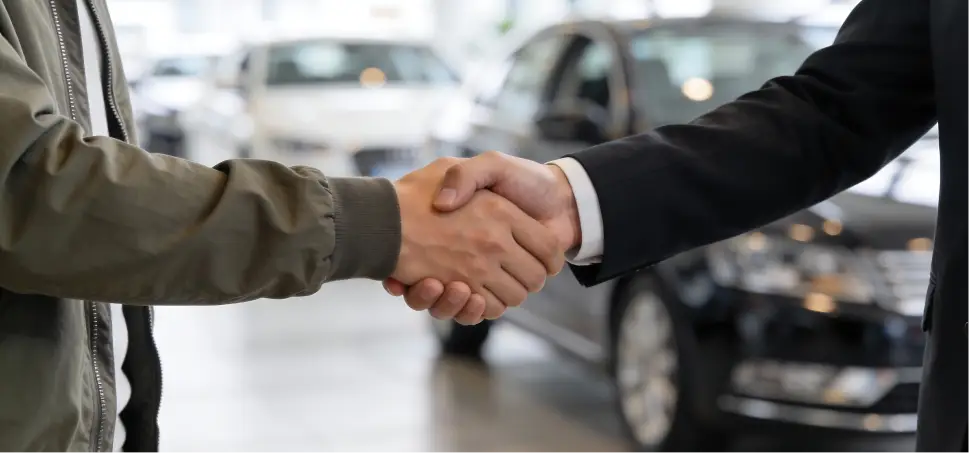 Customer shaking hands with a dealership representative inside a showroom