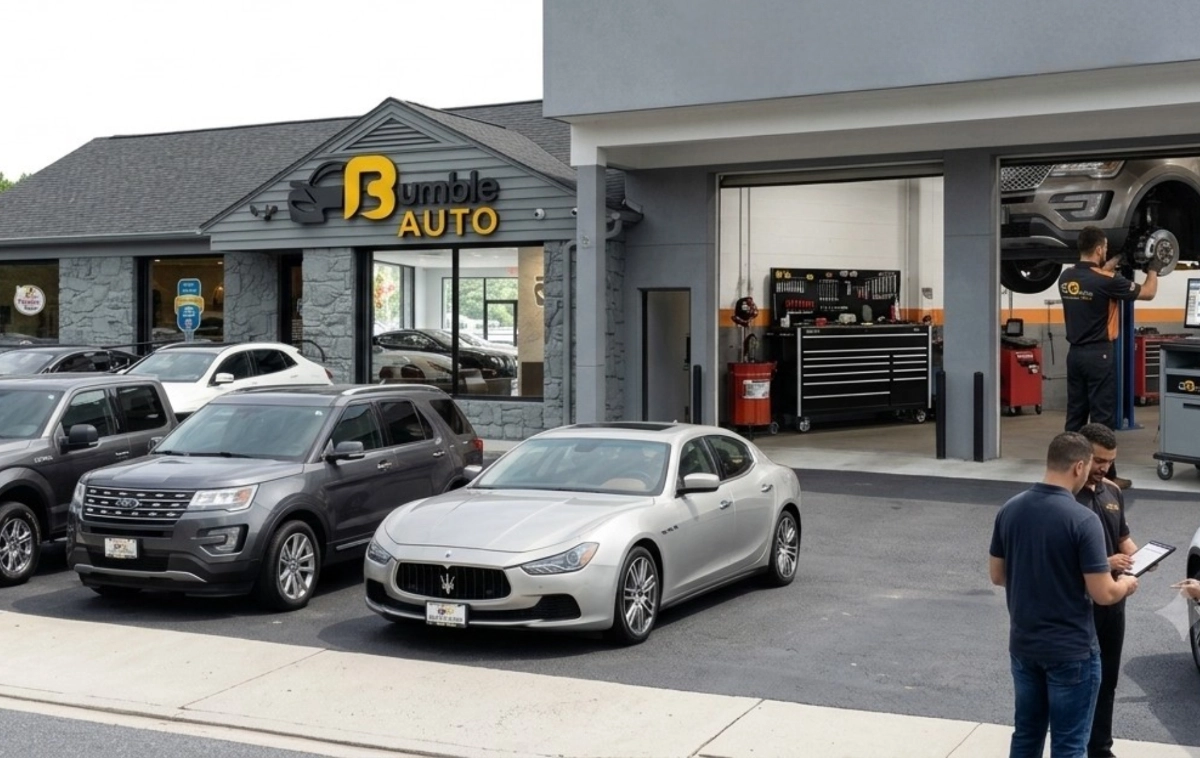 Exterior view of an auto dealership showing parked vehicles, staff assisting customers, and service bays.