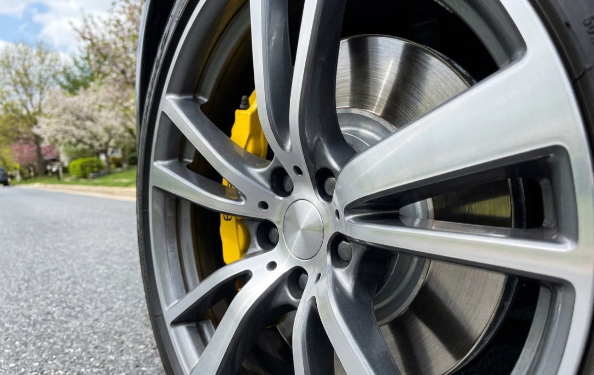 A shiny brake rotor and caliper visible through an alloy wheel.