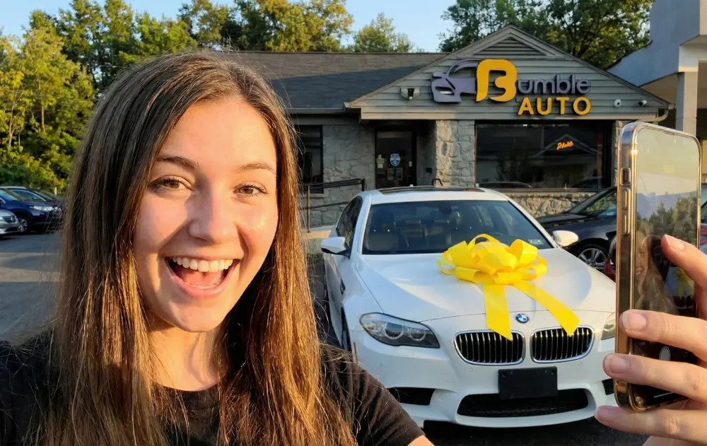Taking selfie in front of dealer with new car