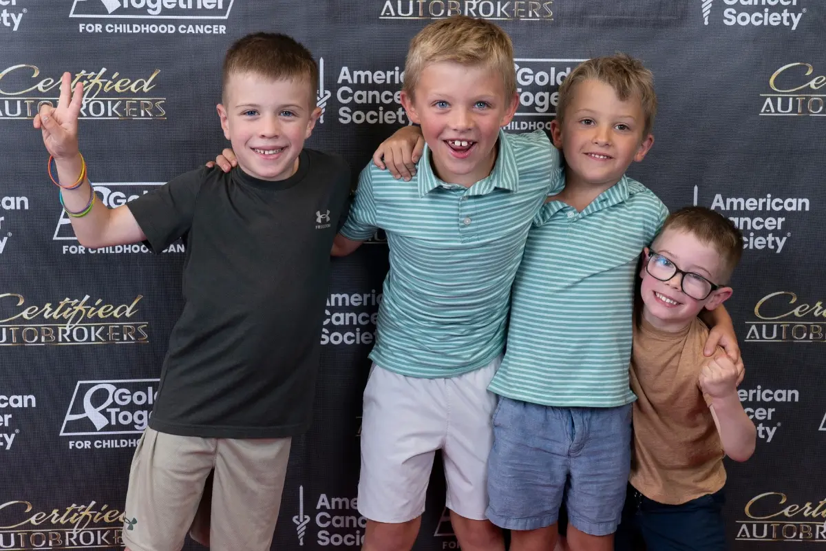 Young guests smiling at the Gold Together photo backdrop during the Drive for a Cure event at Certified AutoBrokers in Grand Island NY