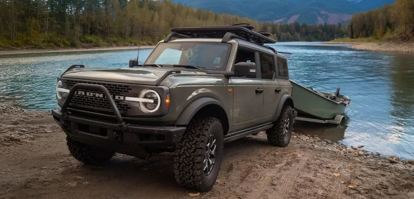 A ford bronco pulling a boat out of teh water.