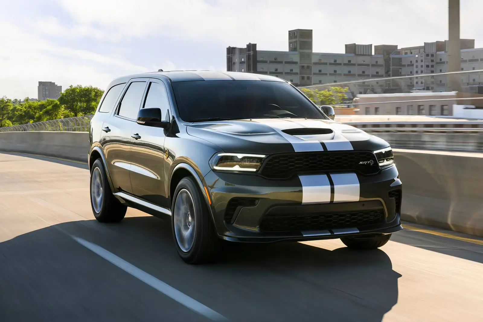 A gray with white stripe suv driving on the road.