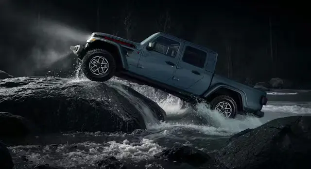 A jeep gladiator sahara driving in the water.